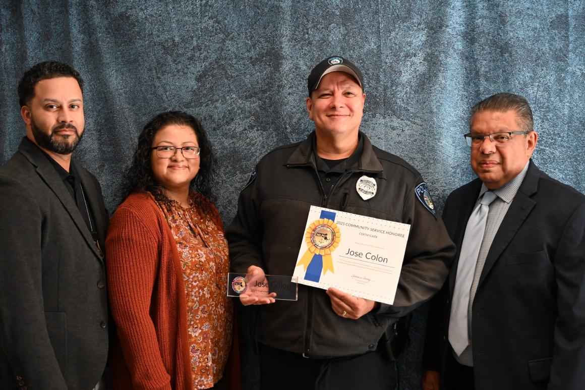 A police officer stands holding a certificate with three other people