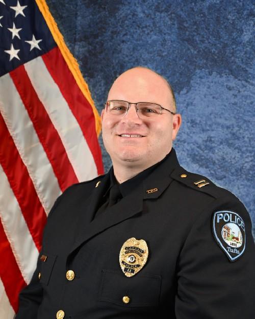 A police officer smiling in front of an American flag