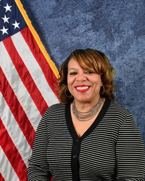 A woman sits for a photo in front of an American flag